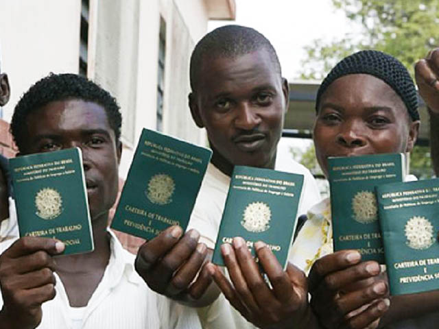 Imigrantes mostrando suas carteiras de trabalho brasileiras